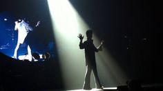 a man standing on top of a stage with his hands in the air