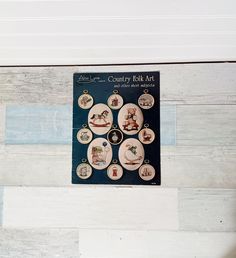 a book about country folk art is displayed on a white wood paneled wall with buttons