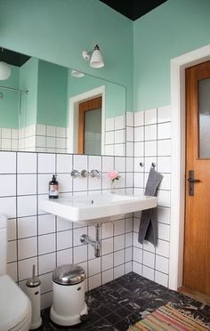 a white toilet sitting next to a sink in a bathroom under two mirrors on the wall