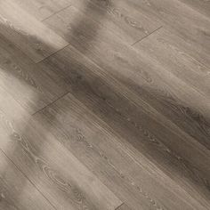 the shadow of a person standing on top of a floor next to a wooden floor