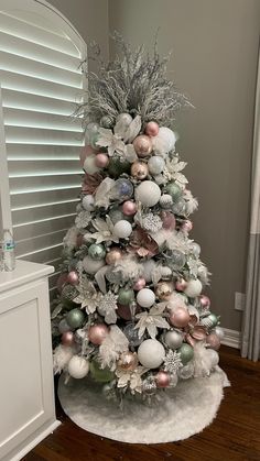 a white christmas tree with pink and silver ornaments