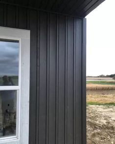 an open window on the side of a building with dirt and grass in the background