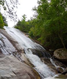 a waterfall in the woods with rocks and trees