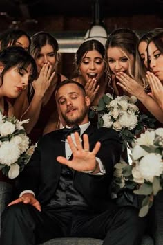 a group of bridesmaids and grooms sitting on a couch with their hands in the air