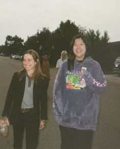 three women are walking down the street with their hands in each other's pockets