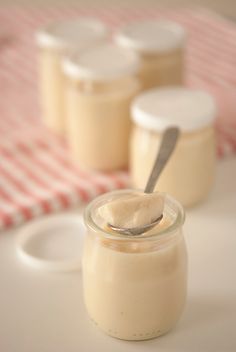 three small jars filled with pudding on top of a white tablecloth and red and white checkered cloth