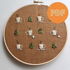 a cross stitch pattern with coffee mugs and christmas trees on the front in brown linen