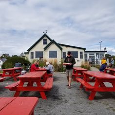 people sitting at red picnic tables in front of a house