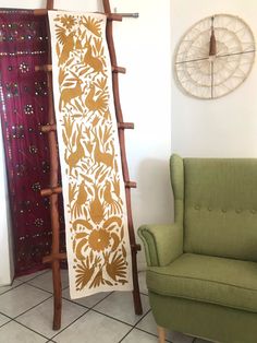 a green chair sitting next to a tall wooden rack with an intricate design on it