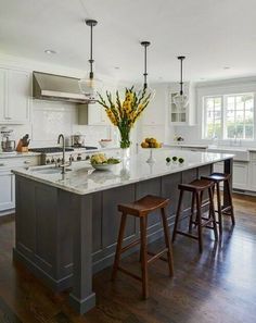 a large kitchen with an island and two stools next to the counter top,