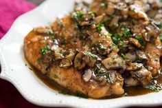 a white plate topped with meat covered in mushrooms