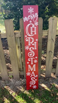 a wooden sign that says merry christmas and is in front of a fence with snowflakes