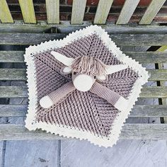 a knitted cow blanket sitting on top of a wooden bench