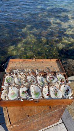 an old wooden box filled with seashells next to the ocean