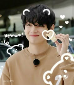 a young man holding up a cookie in front of his face with hearts drawn on it