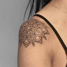 a woman's shoulder with a tattoo design on the back of her left arm