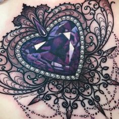 a woman's chest with an intricate design and purple stone in the shape of a heart