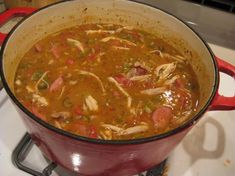 a red pot filled with soup sitting on top of a stove