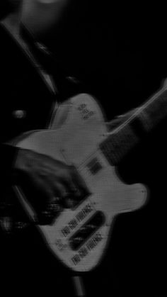 black and white photograph of a man playing an electric guitar with blurry image in the background