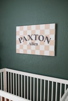 a white crib in front of a green wall with a sign that says paxton alien