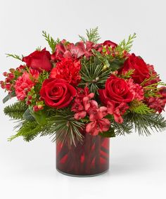 a vase filled with red flowers and greenery