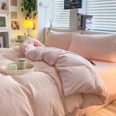 a bed with pink sheets and pillows in a bedroom