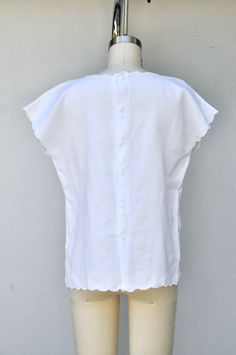 "Vintage White LINEN Blouse *Scalloped hem *Button down back with fabric covered buttons *Sheer *Perforated Hand Embroidered Flower on front *Side Slits *We found this beauty in ITALY Stunning and in Excellent Vintage Condition Tag says : Giglio Size : 40 feels like S - M ( Please refer to measurements ! ) Color : white Fabric : n/a feels like 100% linen Measurements : Neck Aperture : 8\" Shoulders : from one side to other 23 1/2\" Armpit to Armpit : 19 3/4\" waist : 19 1/4\" Hips : 20\" Length: White Scalloped Edges Short Sleeve Top, White Tops With Scalloped Edges And Short Sleeves, White Short Sleeve Tops With Scalloped Edges, White Linen Peasant Top, White Linen Top With Broderie Anglaise Detail, White Linen Top With Broderie Anglaise, Hand Embroidered Blouse, White Linen Blouse, Fabric Covered Button