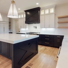 a large kitchen with black cabinets and white counter tops, an island in the middle