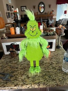 a green stuffed creature sitting on top of a counter