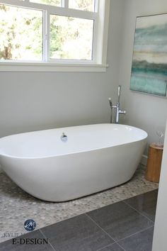 a large white bath tub sitting in a bathroom next to a painting on the wall