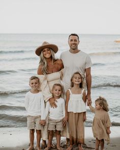 a man, woman and children standing on the beach with their arms around each other