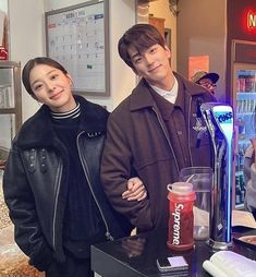 two people standing next to each other in front of a vending machine