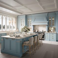 a large kitchen with blue cabinets and white counter tops is pictured in this image, there are many chairs around the island