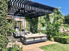 an outdoor living area with couches and flowers on the lawn, surrounded by greenery