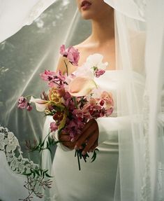 a woman holding a bouquet of flowers under a veil