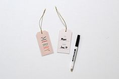 two tags with writing on them next to a pen