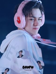 a young man with headphones on wearing a white shirt and pink ear muffs