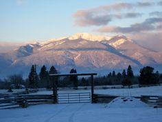 the mountains are covered in snow near a fence