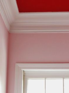 the corner of a room with a window and red painted ceiling in front of it