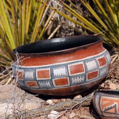 a bowl sitting on the ground next to some plants