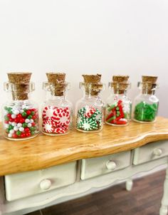 small glass bottles filled with candy canes and candies on top of a wooden table