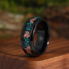 a black ring with flowers on it sitting on top of a wooden table next to a plant