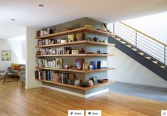 a living room filled with lots of furniture and bookshelves next to a stair case