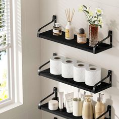 two black shelves holding toilet paper and other bathroom items