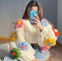 a woman is taking a selfie with her cell phone while sitting on the floor