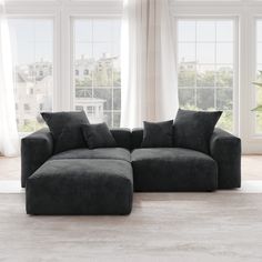 a large gray couch sitting in front of two windows