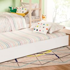 a child's bed with colorful striped sheets and pillows