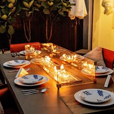 a long table with plates and candles on it in front of a fire place setting