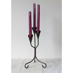 three purple candles sitting on top of a metal stand