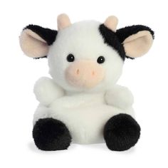 a white and black stuffed cow sitting up against a white background